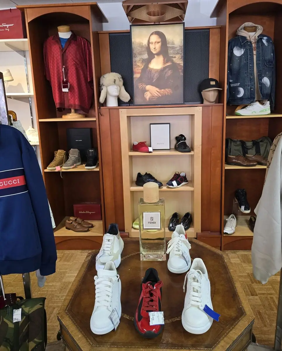 White designer sneakers displayed on a table in front of the Gucci and Fendi shelf