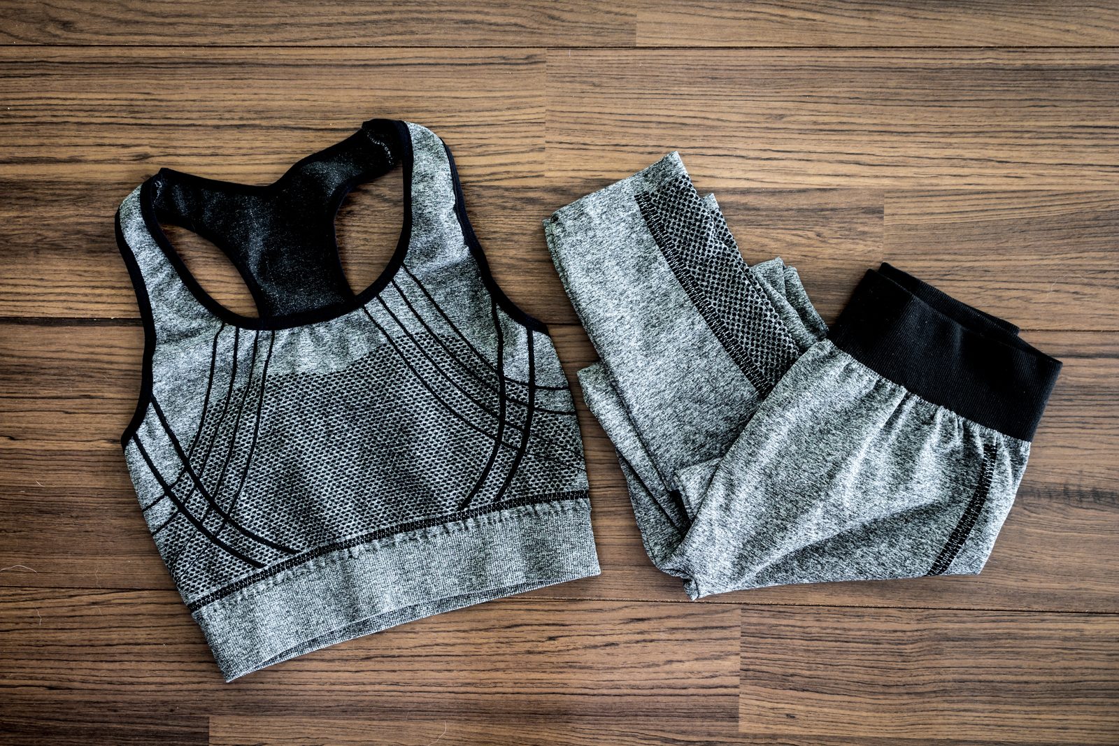 Grey sports bra and seamless shorts set laid out on a wood floor