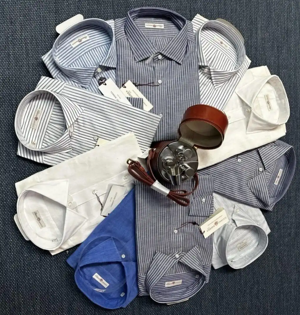 Luciano Barbera striped and linen dress shirts laid out in a circle with a leather travel case